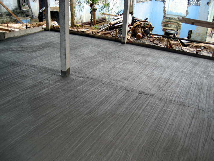 Newly poured concrete slab foundation at a residential construction site.