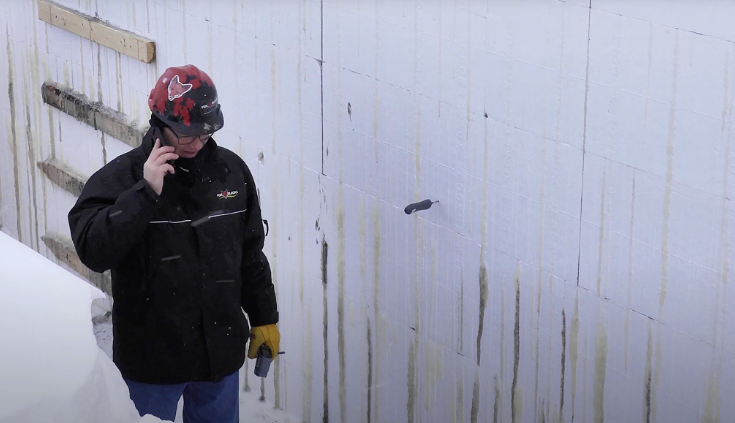 Worker inspecting an insulated concrete form wall at a construction site.