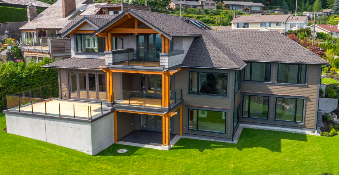 Large modern custom home with expansive windows and multiple outdoor living spaces.