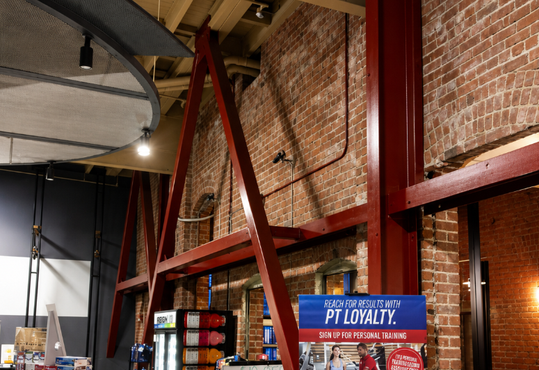 Exposed brick commercial interior reinforced with red structural steel beams.