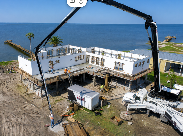 ICF building under construction with a concrete pump near the waterfront.