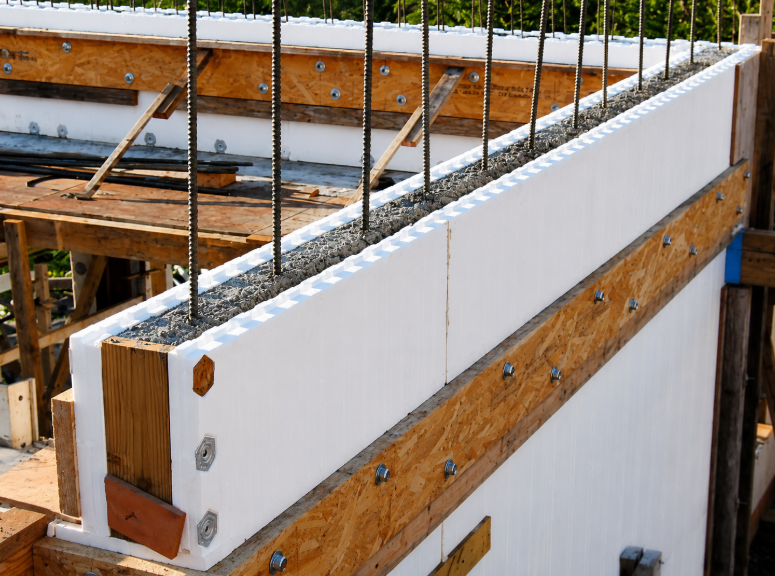 Close-up of an insulated concrete form wall under construction with vertical steel rebar and wooden bracing.