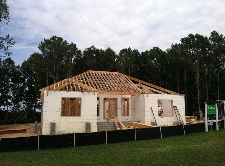 ICF home under construction with concrete form walls and wooden roof framing.
