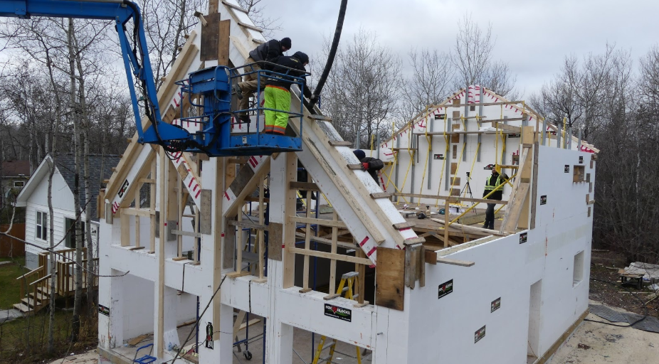 Workers constructing a house with insulated concrete forms for energy-efficient walls and roofing.