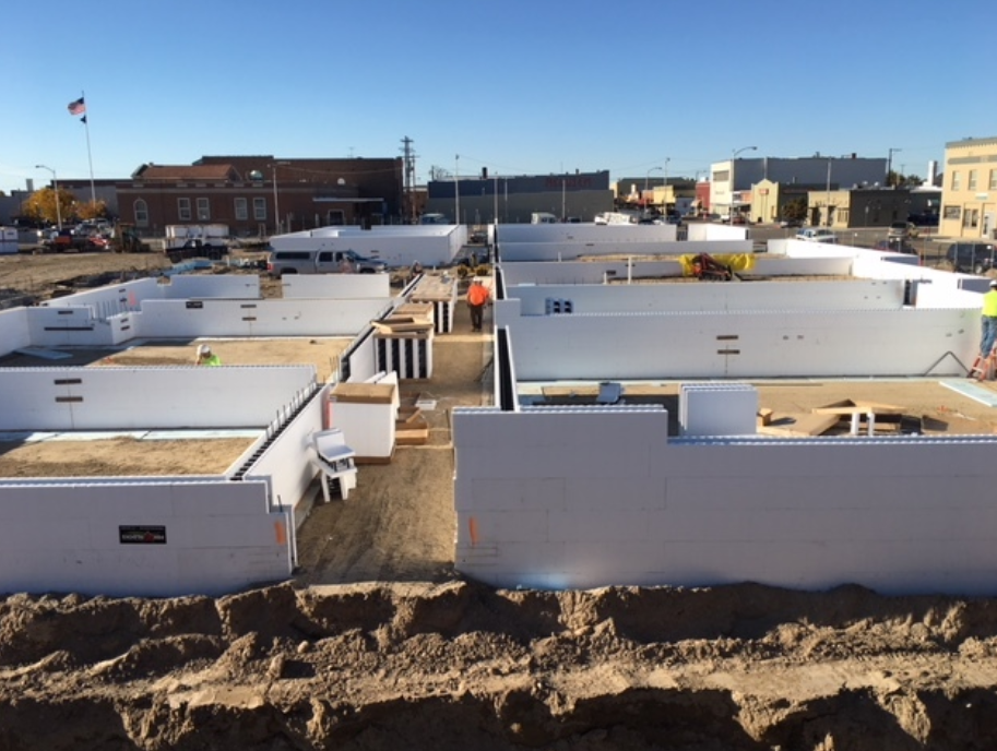 Early construction stage of a movie theater with insulated wall forms outlining rooms across the site.