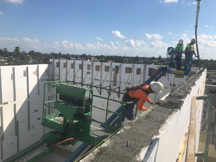 Construction crew pouring concrete walls during distribution center construction.