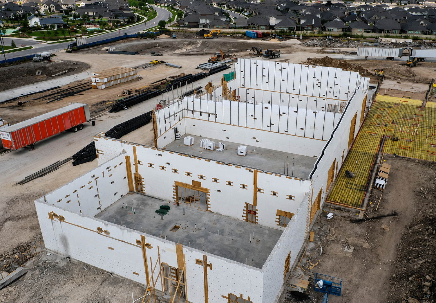 Commercial building under construction with insulated concrete form (ICF) walls and reinforced concrete slab foundations.